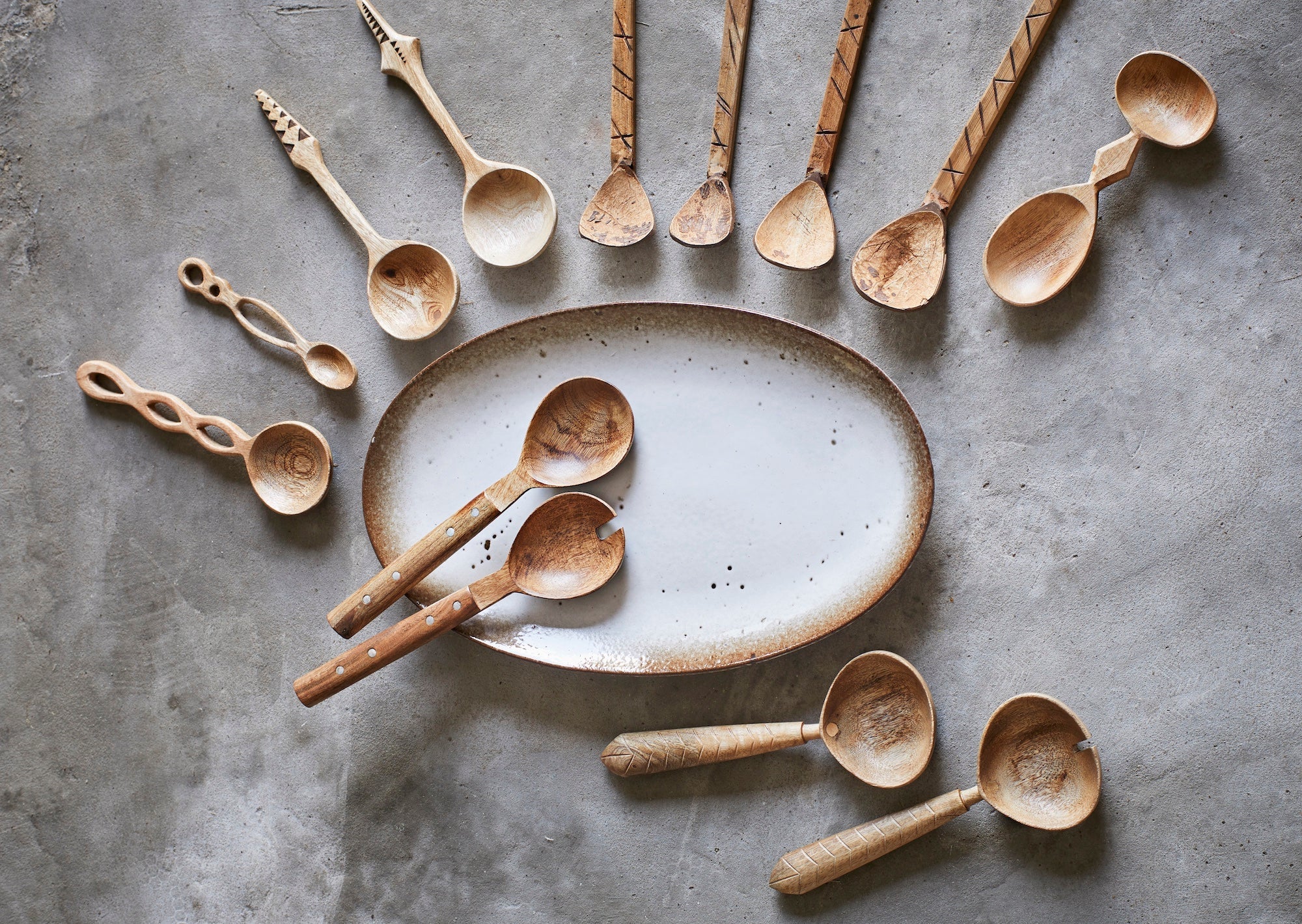 oval ceramic serving platter styled with wooden spoons on neutral surface
