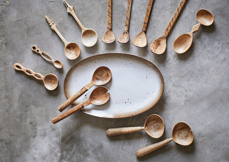 oval ceramic serving platter styled with wooden spoons on neutral surface
