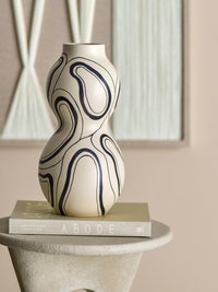 Organic black line vase displayed on neutral pedestal with art book