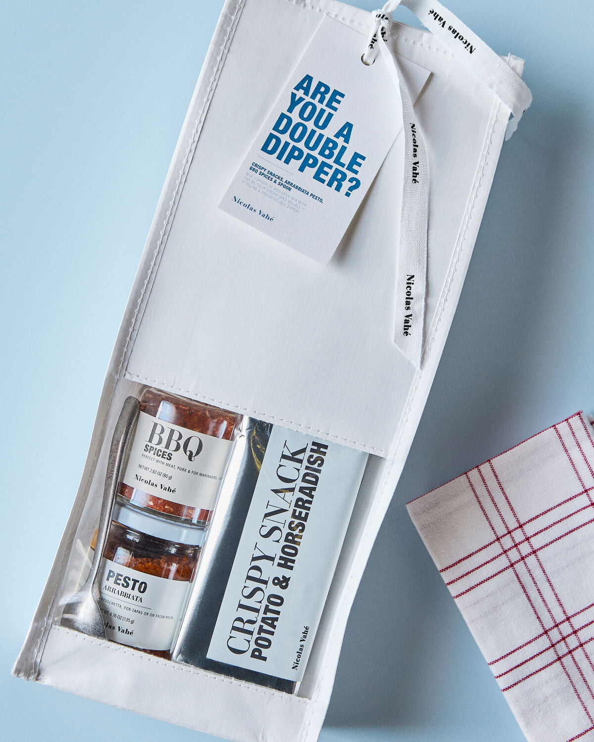 Nicolas Vahé Are You a Double Dipper gift bag on a pale blue surface with a checked napkin