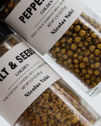 Close-up of Nicolas Vahé golden pepper mix and golden salt and seeds grinder labels