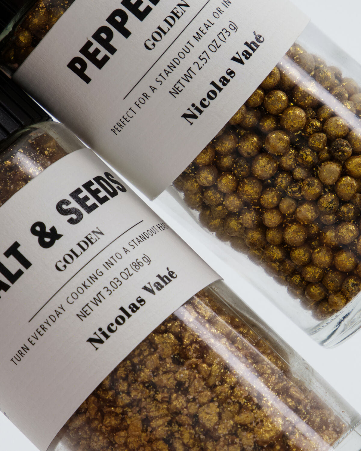 Close-up of Nicolas Vahé golden pepper mix and golden salt and seeds grinder labels