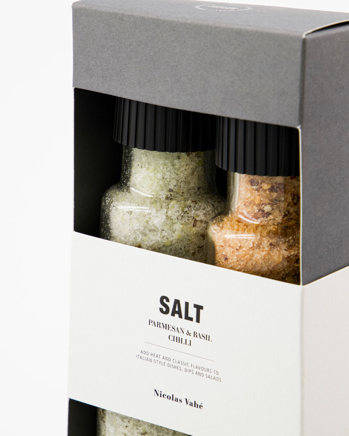 Close-up of the Nicolas Vahé Parmesan and basil and chilli salt grinders inside the gift box