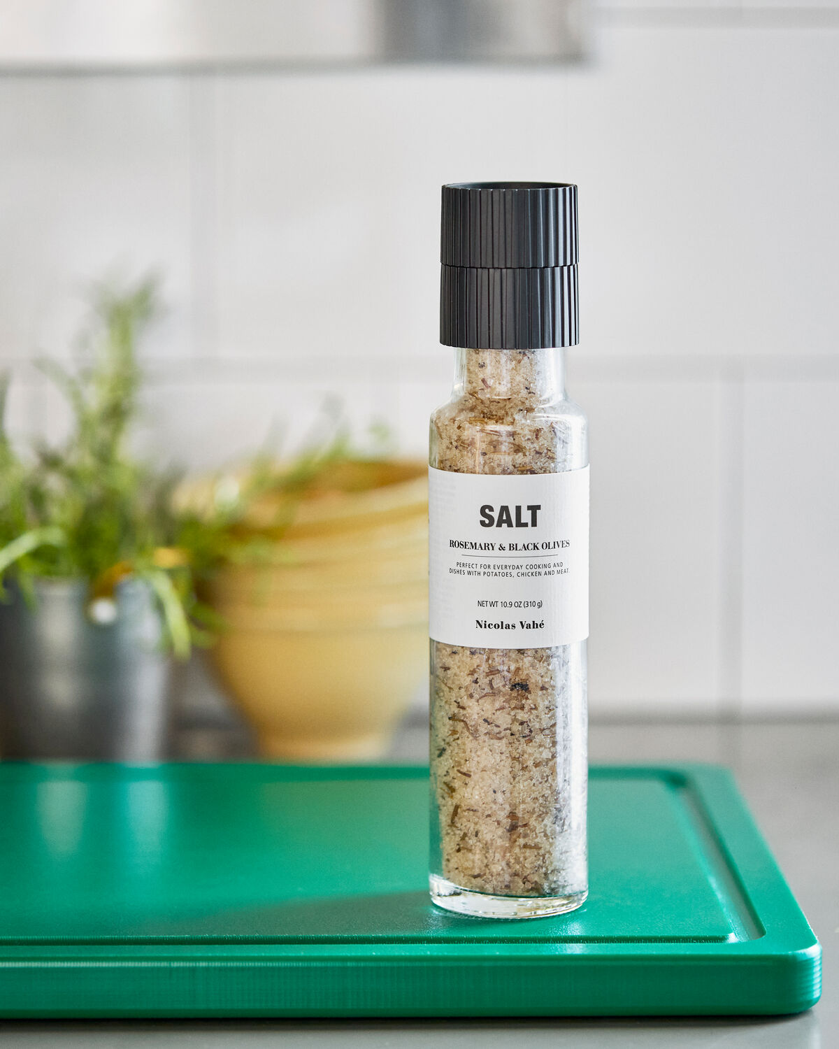 Nicolas Vahé rosemary and black olive salt grinder on a green chopping board in a tiled kitchen