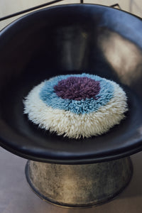 round fluffy HKLIVING cushion in cream blue and plum adding texture and warmth to a dark accent chair
