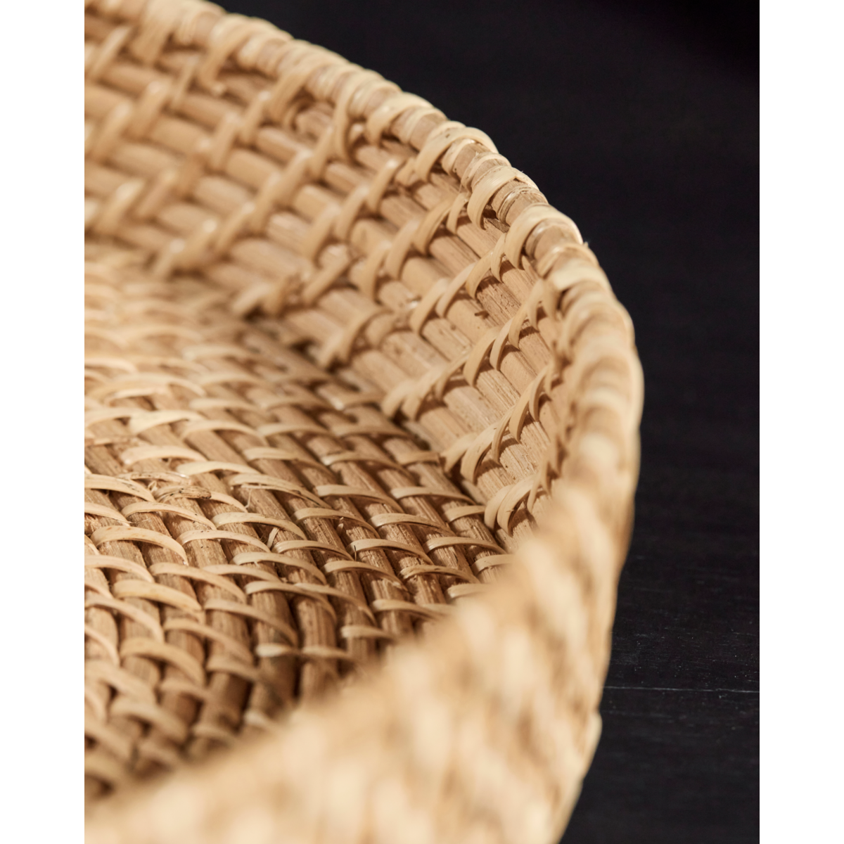 round rattan serving tray on dark wood table interior scene
