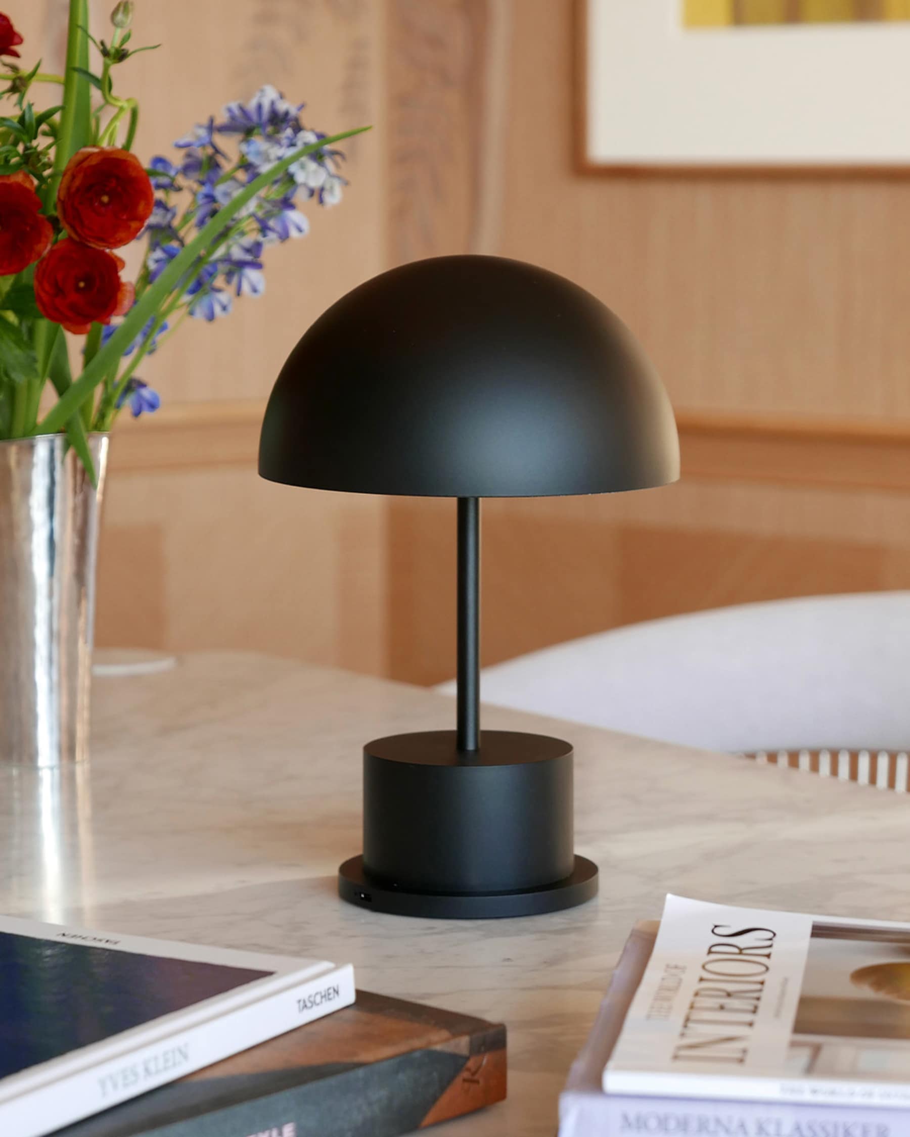 black Riviera rechargeable lamp on marble table with flowers and books
