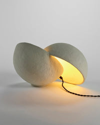 Earth split sphere lamp by Marie Michielssen glowing on a surface, side view