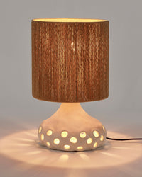 Serax Oya table lamp switched on, light glowing through the shade and dotted base