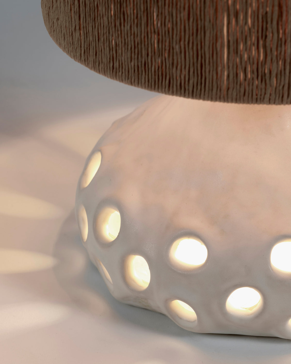 Close-up of the perforated beige stoneware base of the Serax Oya table lamp