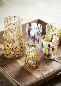 coloured drinking glass styled on wooden table with matching glassware
