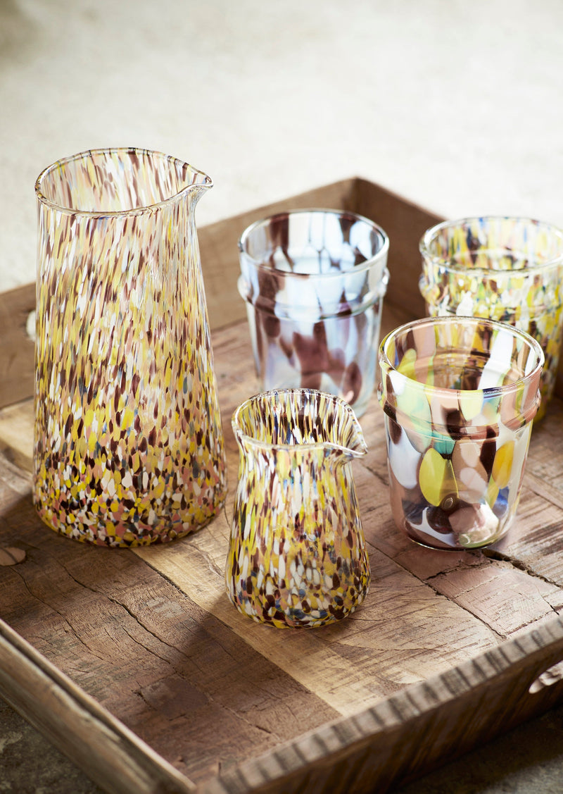 coloured drinking glass styled on wooden table with matching glassware

