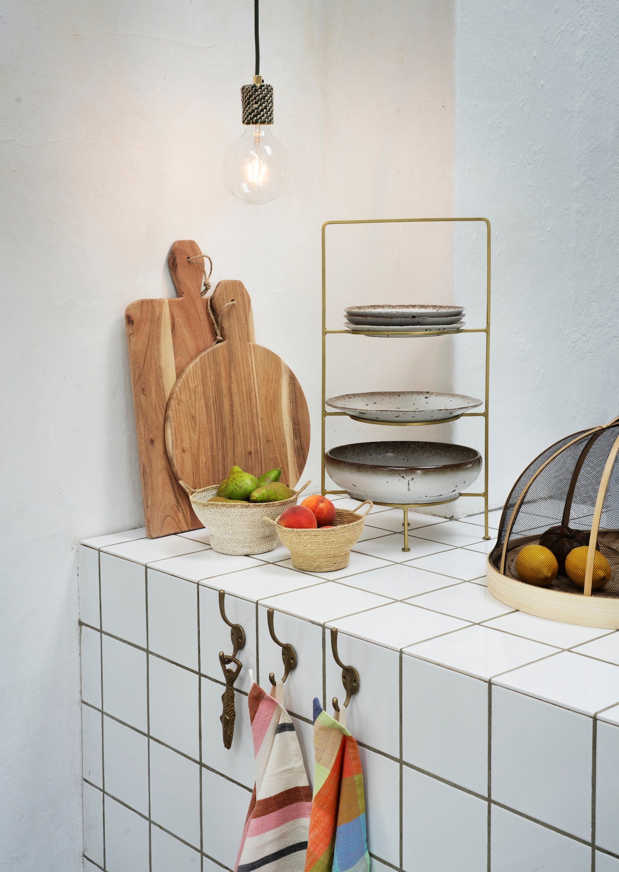 Kitchen counter with cutting boards, bowls of fruit, and a small shelf with plates.