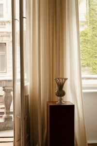 Stria vase by Olsson & Jensen on a dark wood plinth by a window
