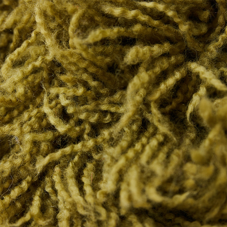 Close-up of olive green shaggy cushion on sofa, fluffy wool blend texture by HKLIVING
