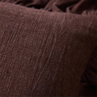 Close-up of woven cotton texture and ruffled trim on chestnut brown cushion
