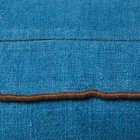 close up of the brown piping around the edge of a blue cushion also shwoing the fabric covering the zipper