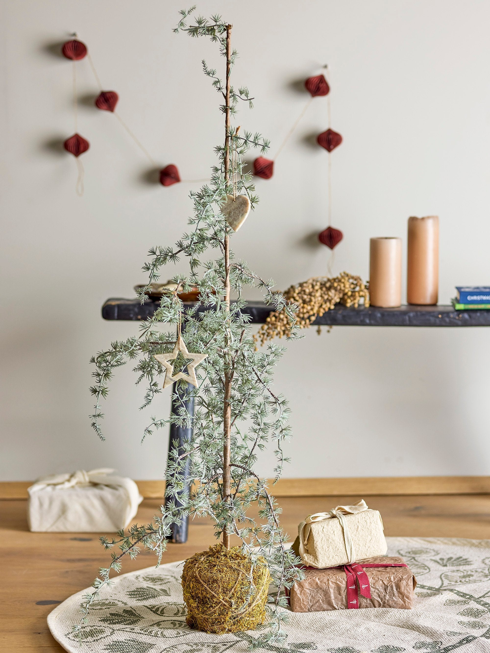 Small artificial pine tree styled on wooden dining table with natural Christmas décor