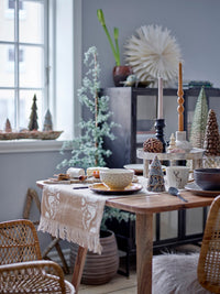 Artificial pine tree with jute base and hanging ornaments beside wrapped gifts