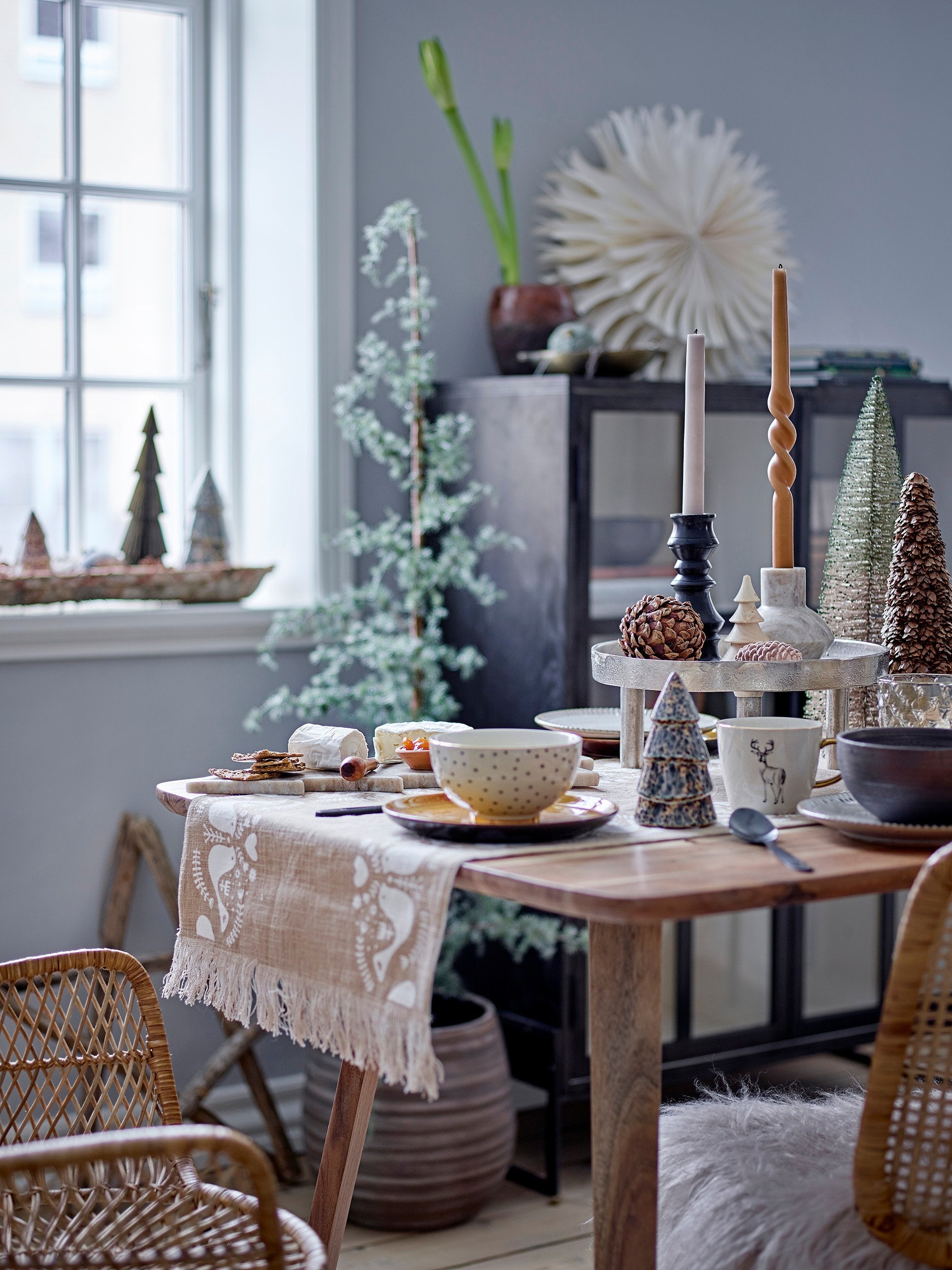 Artificial pine tree with jute base and hanging ornaments beside wrapped gifts