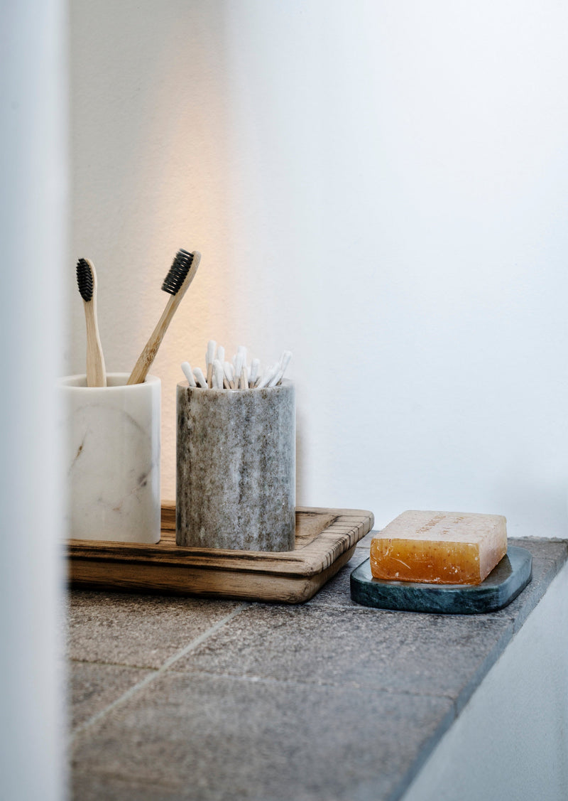 white marble jar used for toothbrushes and bathroom storage in a calm minimalist setting
