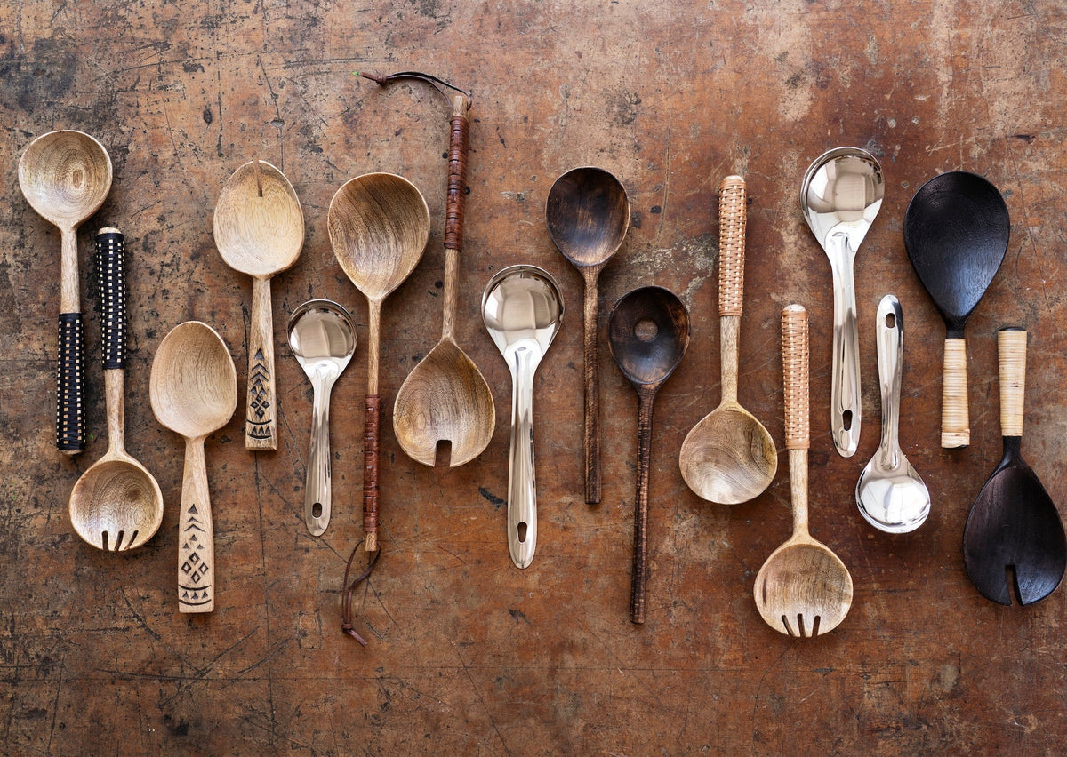 natural wooden kitchen utensils and salad servers arranged on rustic table surface