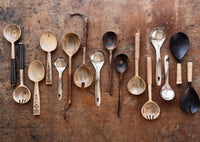 natural wooden kitchen utensils and salad servers arranged on rustic table surface