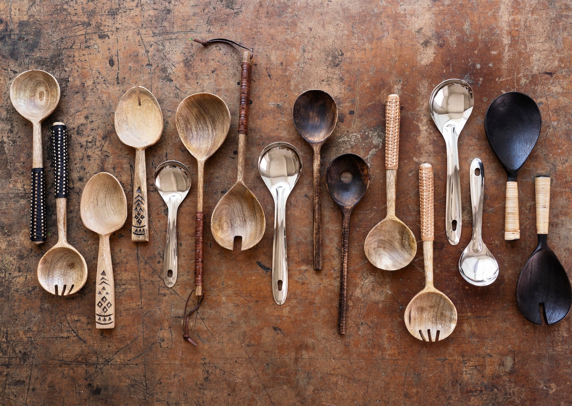 natural wooden kitchen utensils and salad servers arranged on rustic table surface